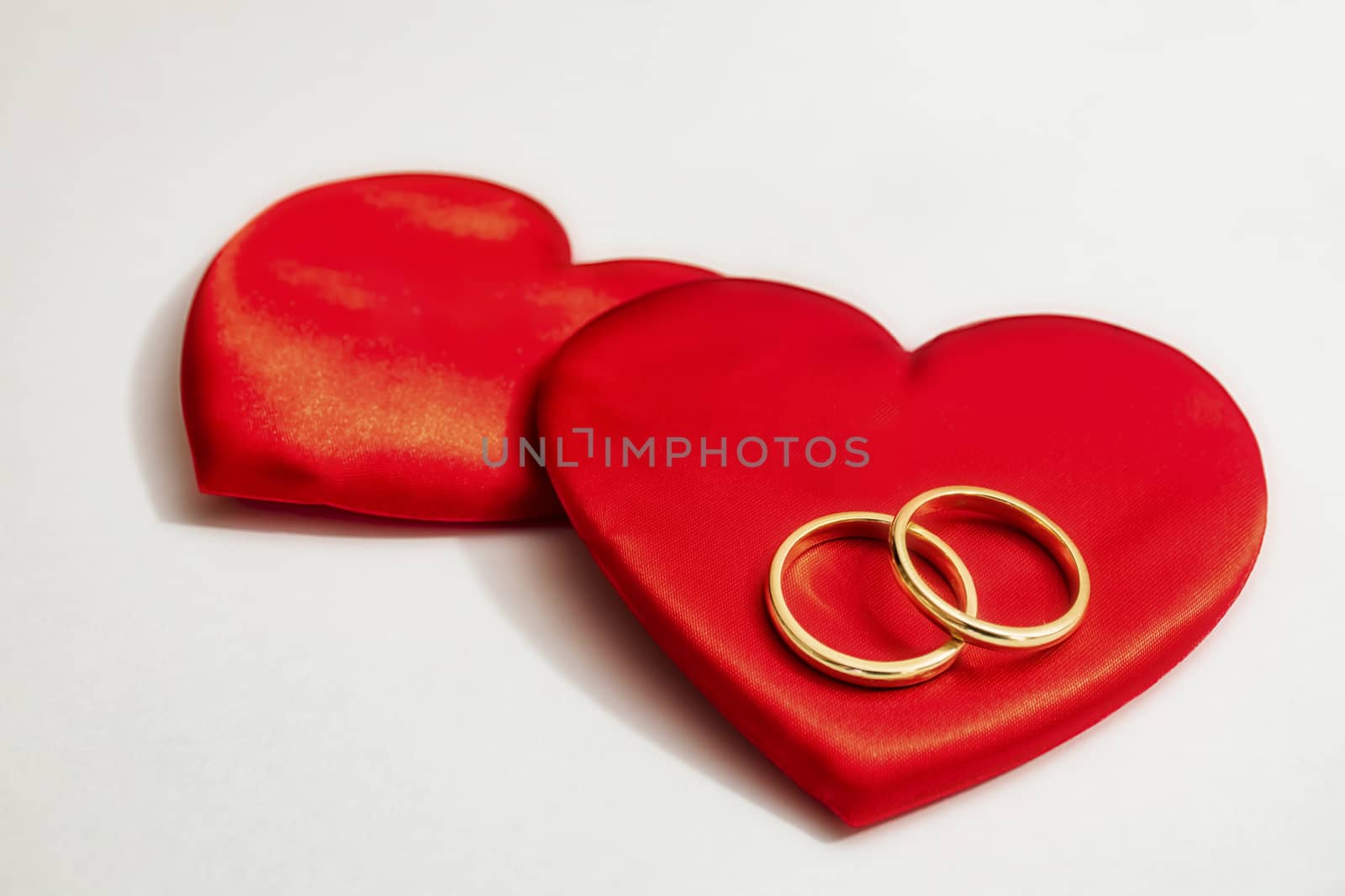 red hearts and wedding rings on a white background