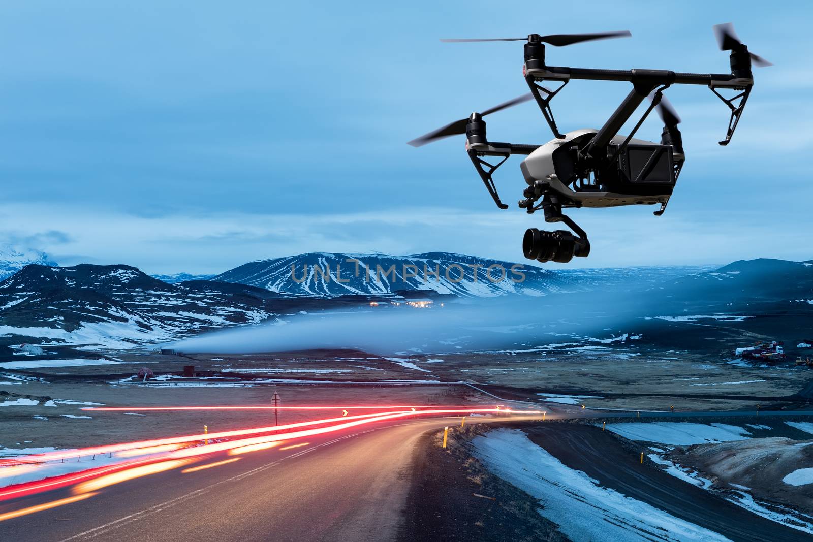 drone quad copter with a camera flies over a road with car lights