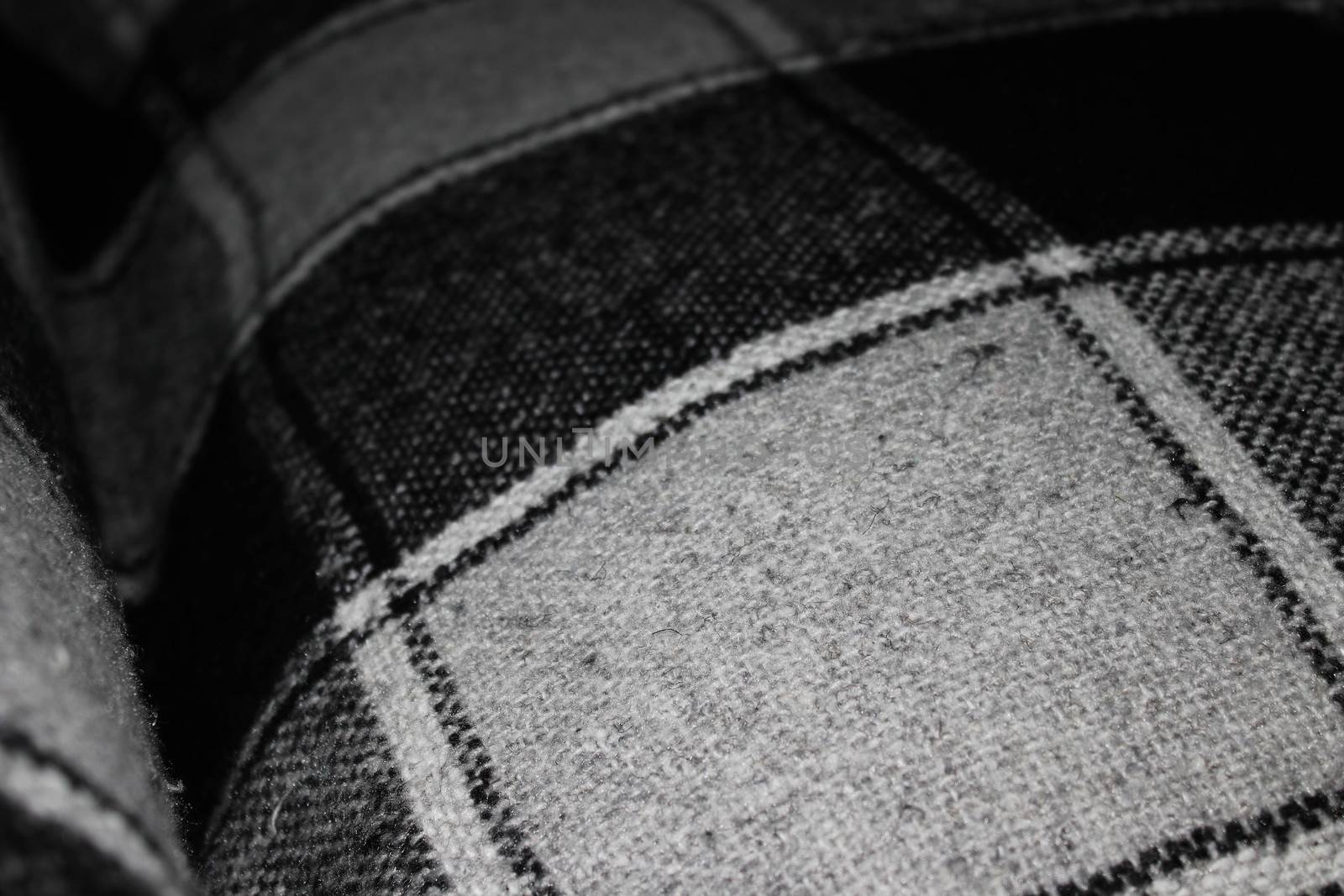 The texture of the knitted plaid in a cell in gray-black