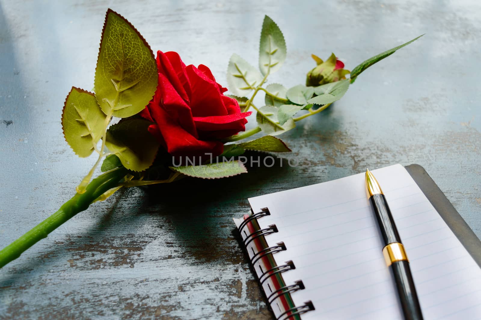 Blank Page Notebook, pen and a Beautiful red rose on rustic metal floor background with copy space. Love letter Writing Proposal or propose concept for valentines day wedding and holidays. Top view.