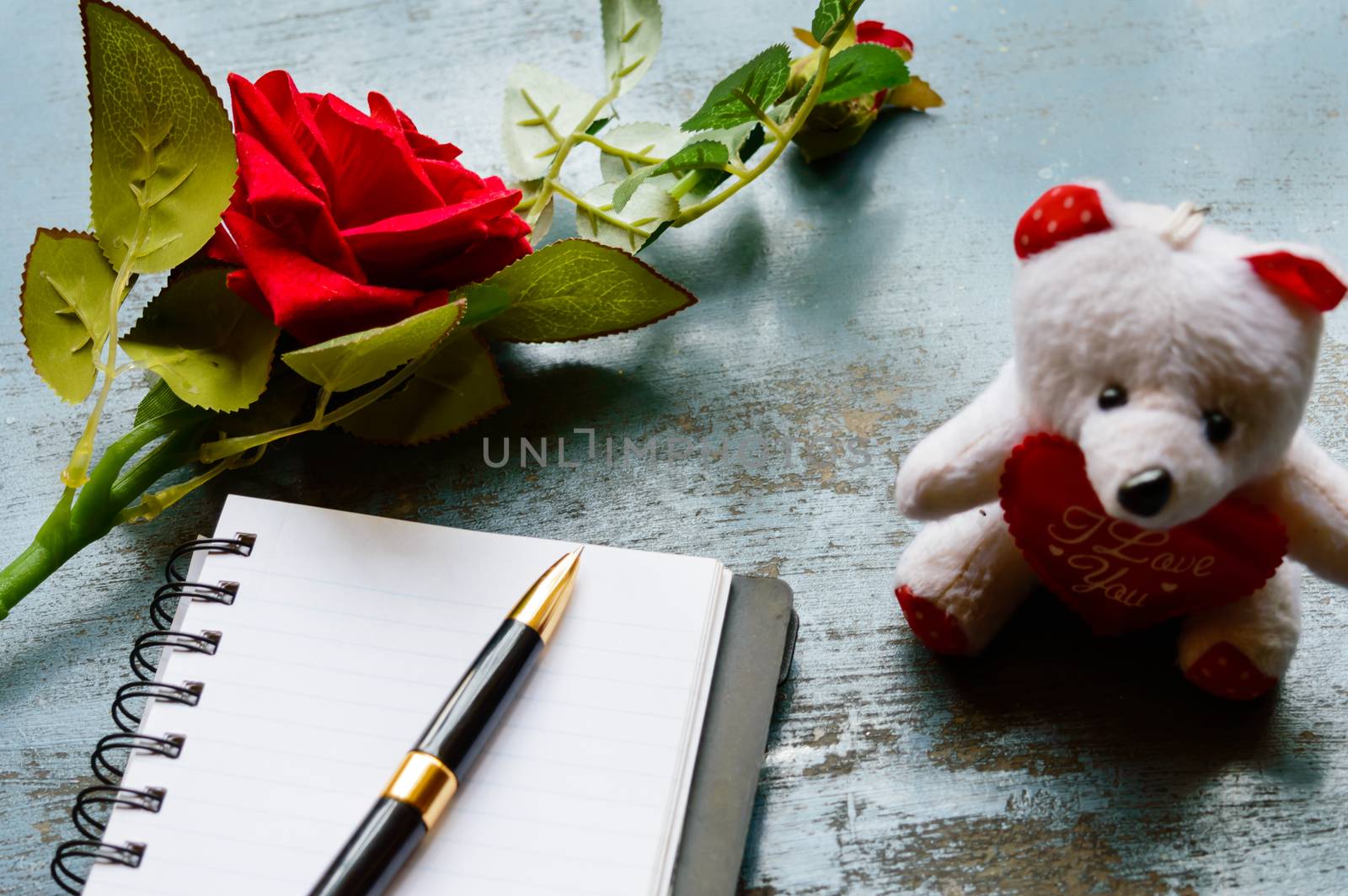 Blank Page Notebook, pen, a beautiful red rose on rustic metal floor background placed near a teddy. Love letter Writing Proposal or propose and waiting concept for valentines day holidays Top view.