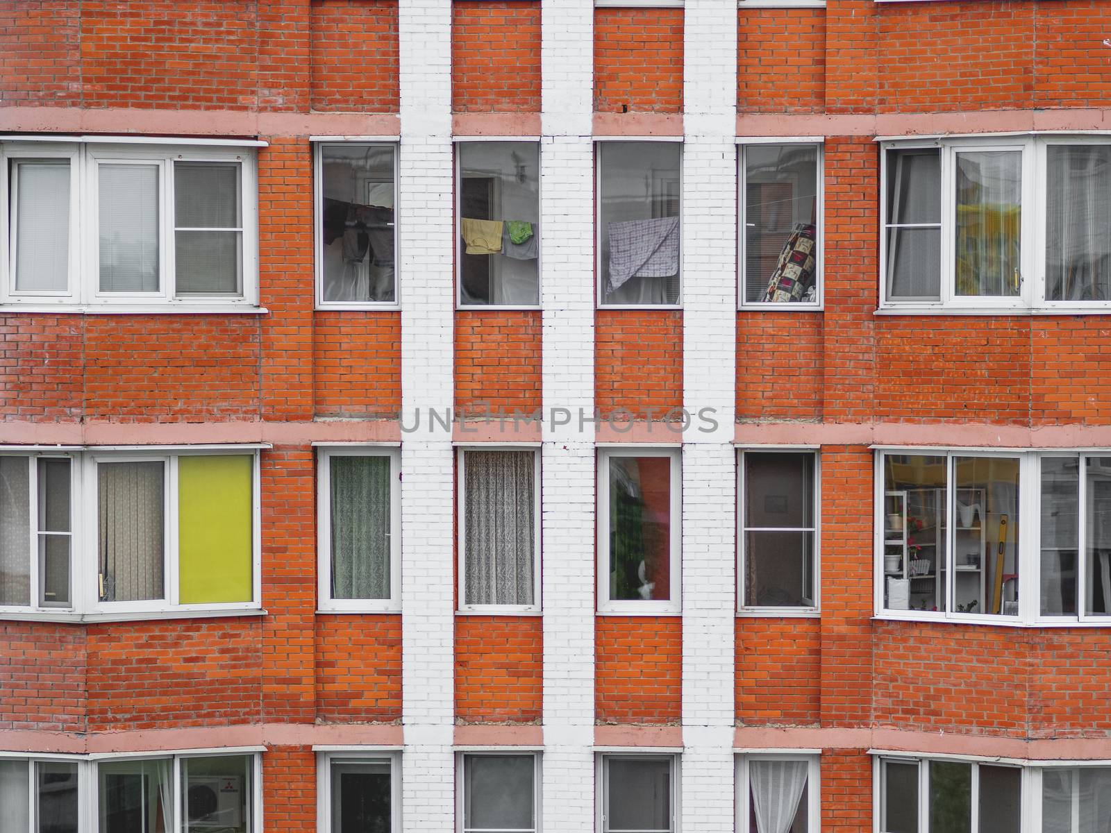 Windows of modern residential apartment building. People use lodge as storage for various things and as dryer for wet clothes.