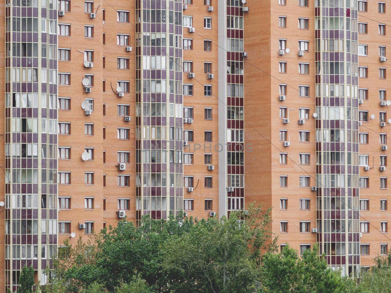 Modern residential apartment building. Lots of air conditioning and satellite plates on the walls of the building.