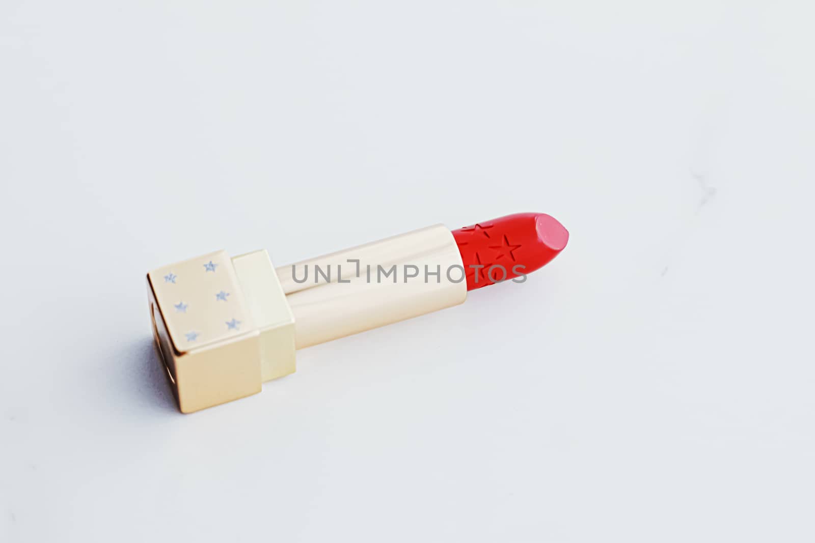 Luxury lipstick in a golden tube on white marble background, make-up and cosmetics concept