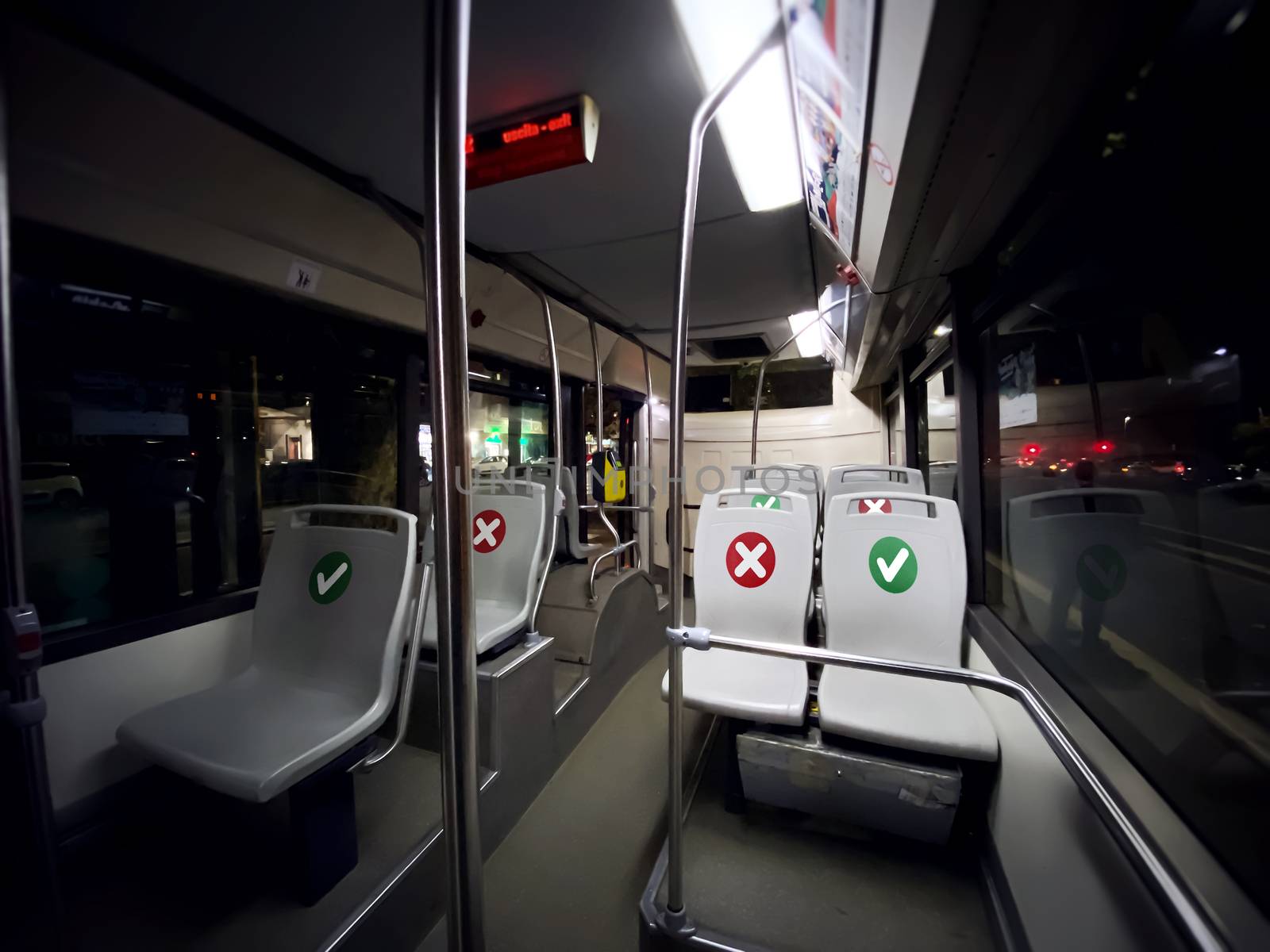 interior of a public transport bus with empty seats with the indication of where is possible to sit during the coronavirus pandemic. Transport and urban mobility. Wide angle shot