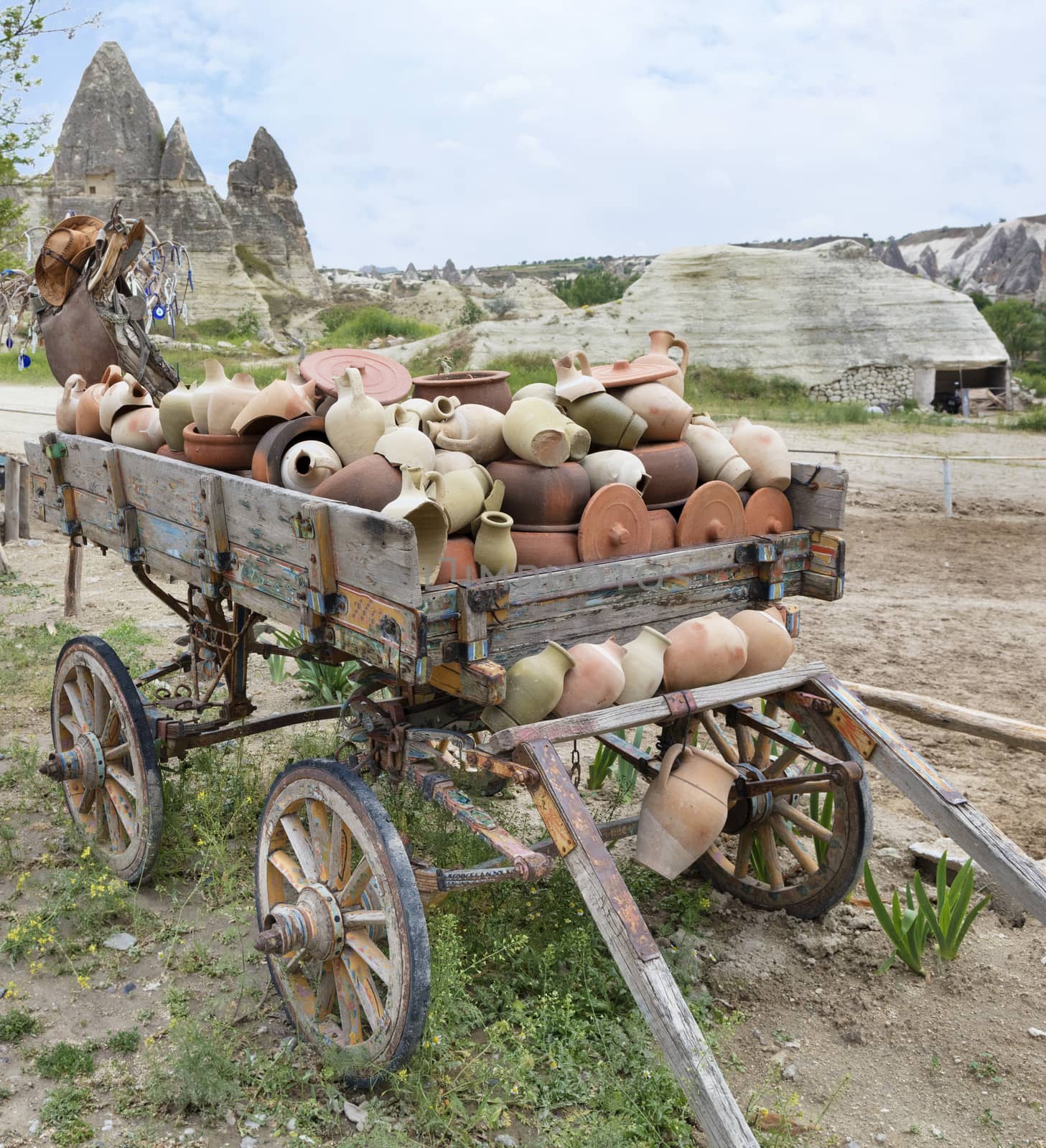 On an old wooden cart, a pile of clay jugs and pots by Sergii