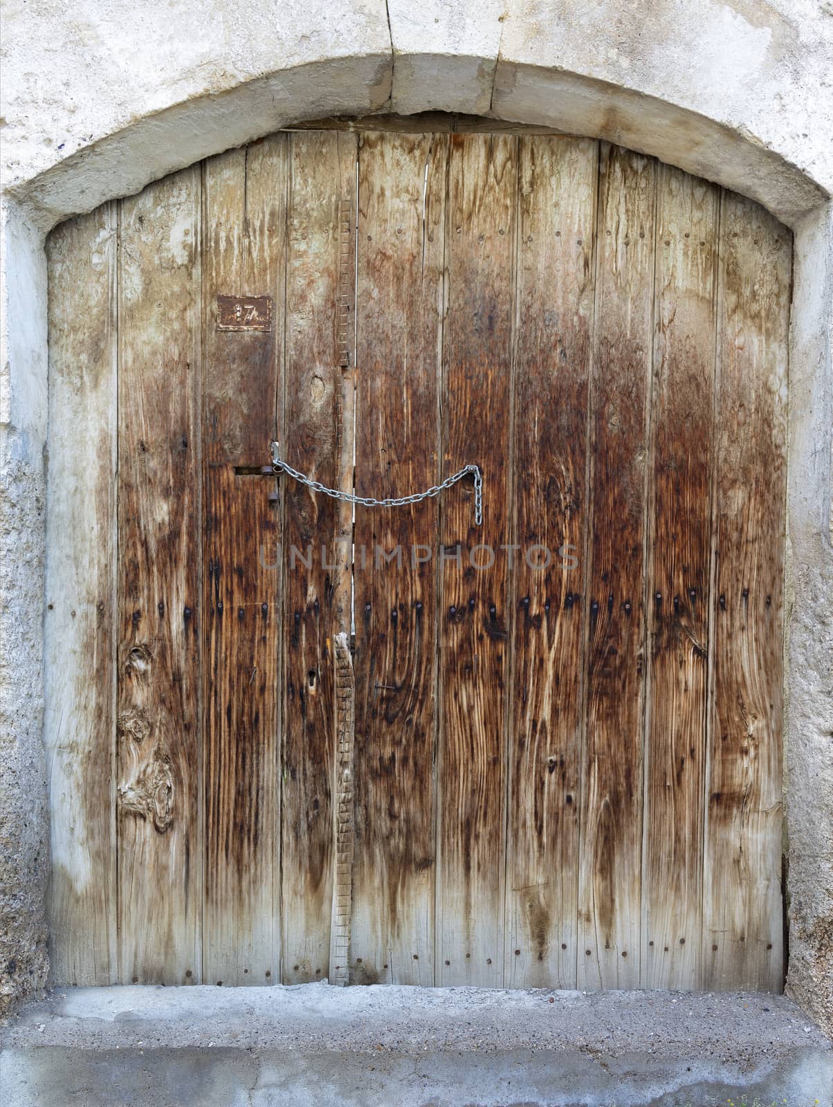 Very old weathered trapezoidal antique wooden doors with a metal wrought iron lock and chain