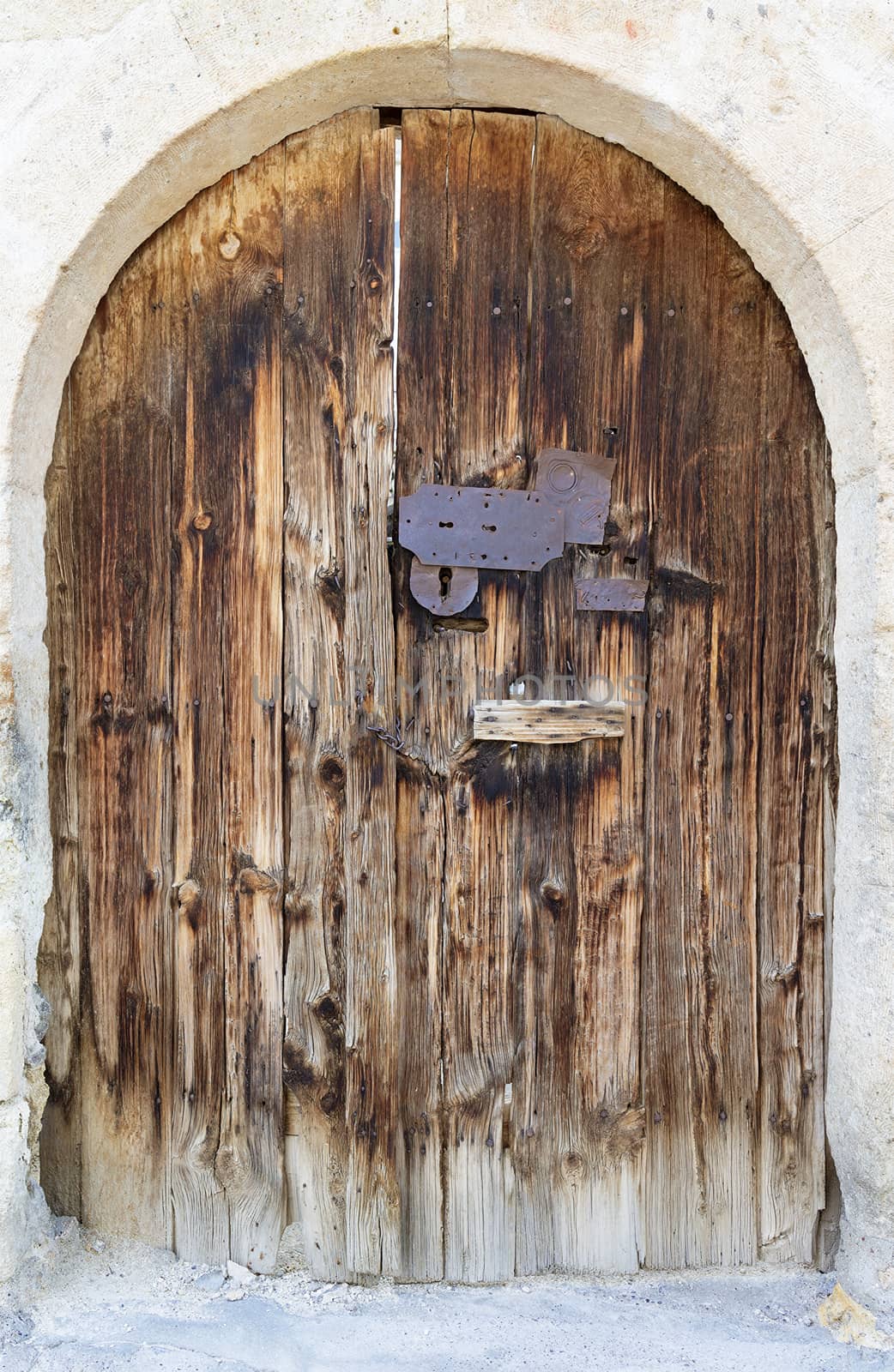 Ancient arched antique wooden doors with a metal lock in the middle by Sergii