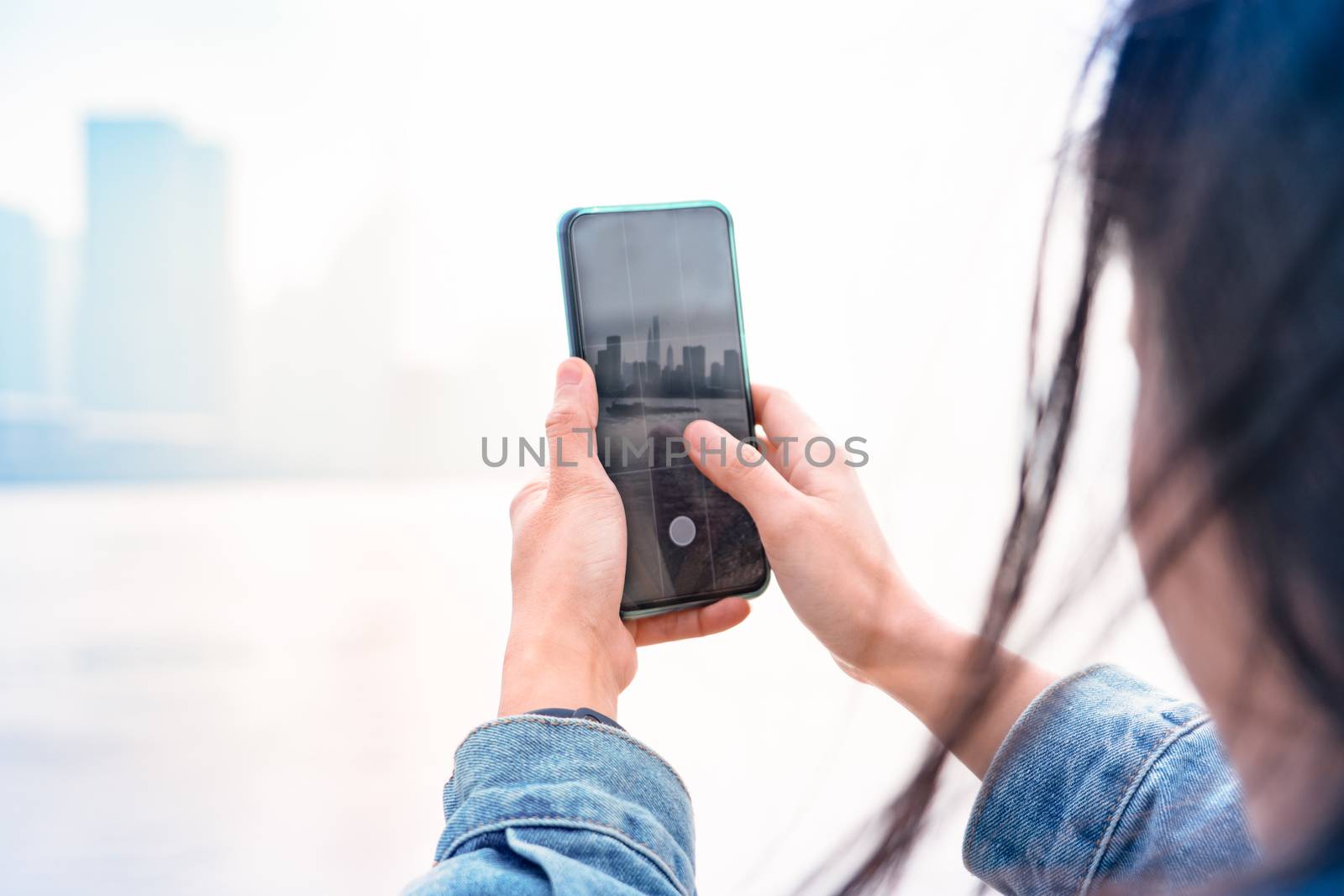 Cityscape on smartphone. View through the screen at Shanghai City on women screen, China.