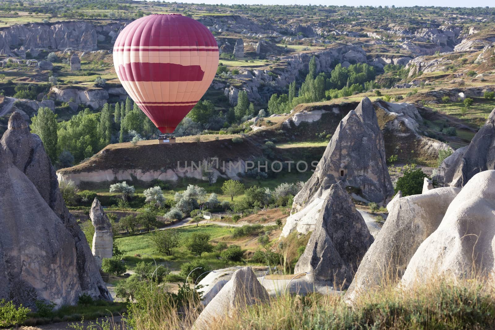 A view of a red balloon flying over the Valley of the Doves at dawn. Cappadocia, Turkey.