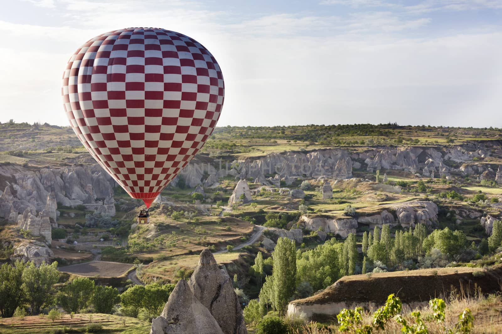 A view of a red balloon flying over the Valley of the Doves at dawn. Cappadocia, Turkey.