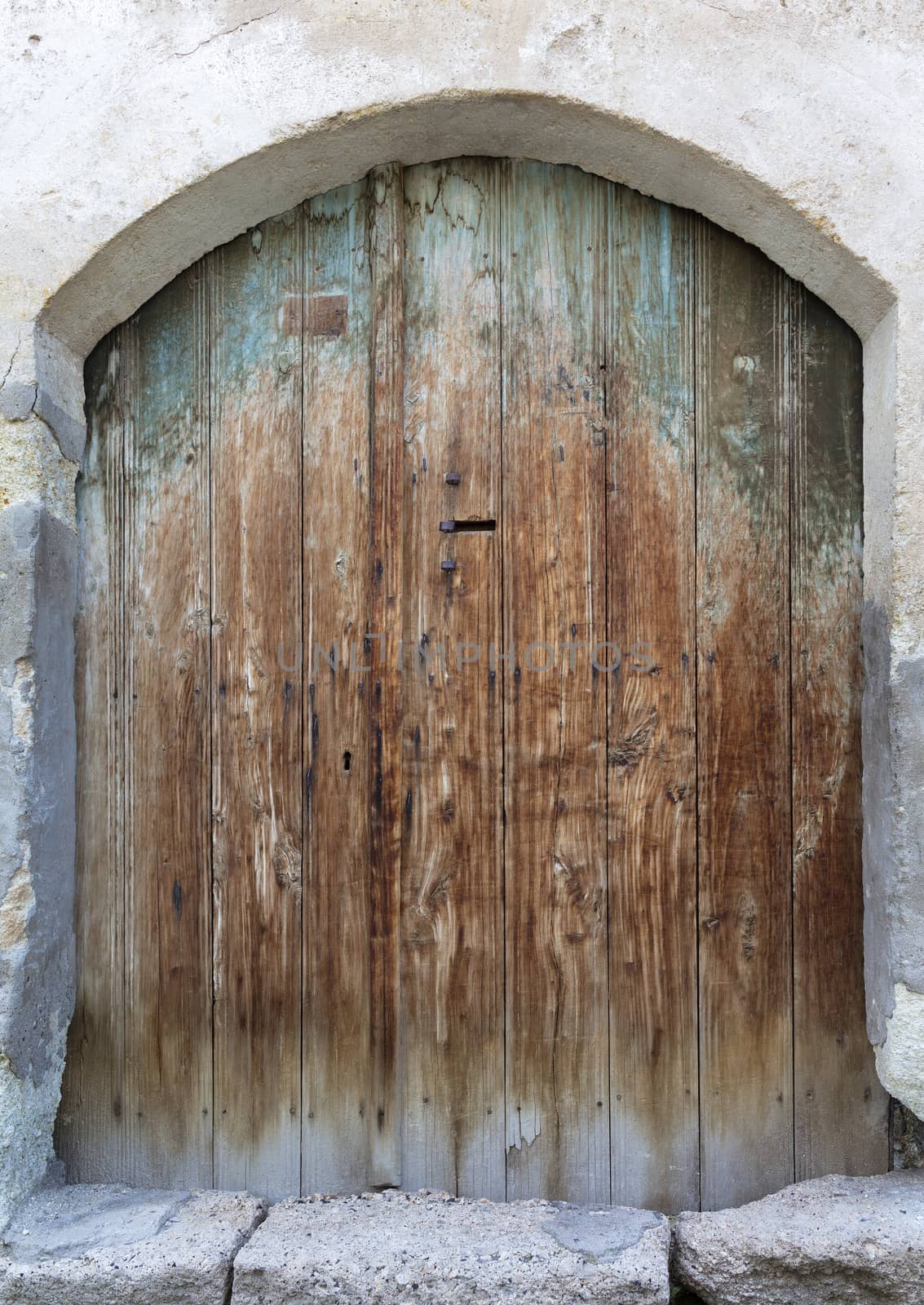 Ancient arched antique wooden doors with a metal lock in the middle by Sergii