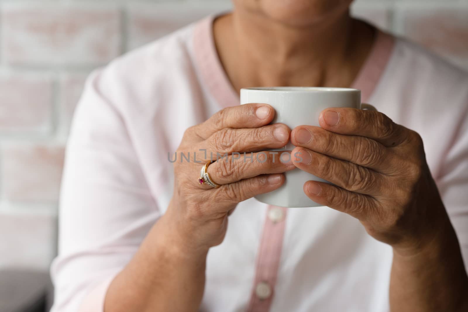 Old woman hold a cup of hot coffee drink at home