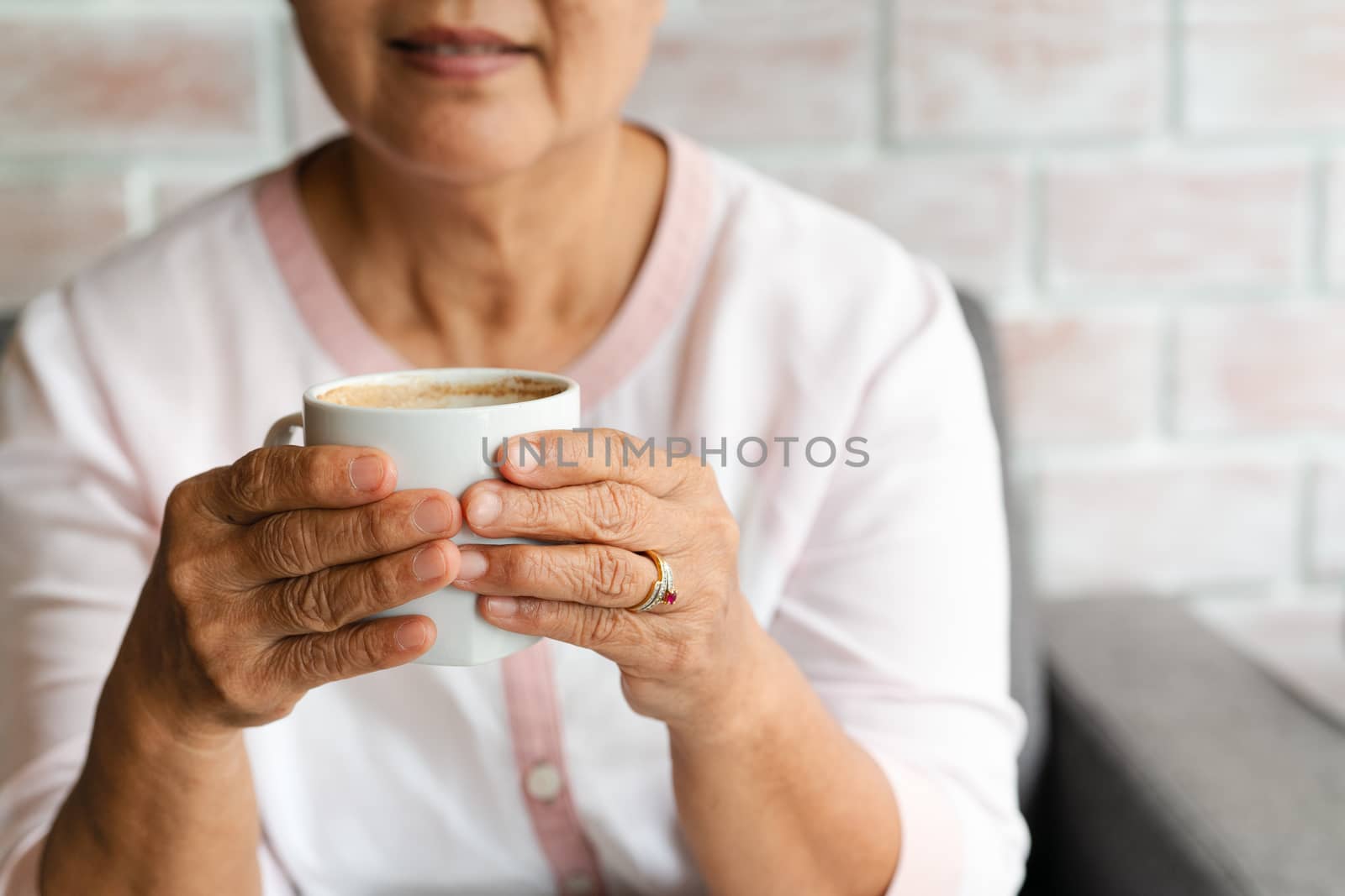 Old woman hold a cup of hot coffee drink at home