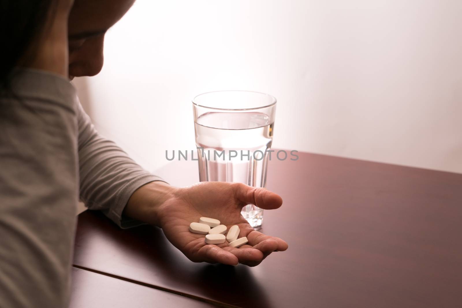underexpose of the headache women hand holding the medicine with a glass of water, medicine recovery concept