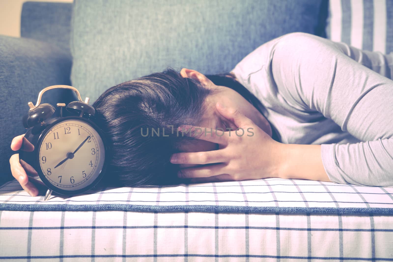 Lazy women is laying down on the sofa after the clock alarm, late wakeup lifestyle concept