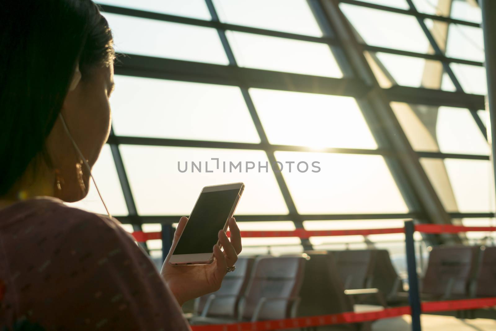 young women watching on mobile phone waiting for flying at airport window