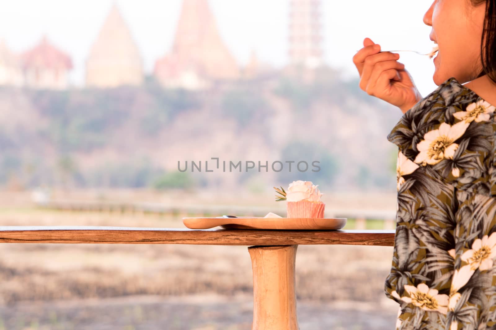 happy girl eating tasty cute cupcake on the wooden table