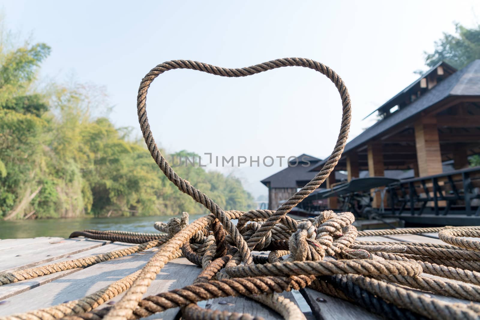 closeup thick rope tie the heart shape on the wooden terrace near river