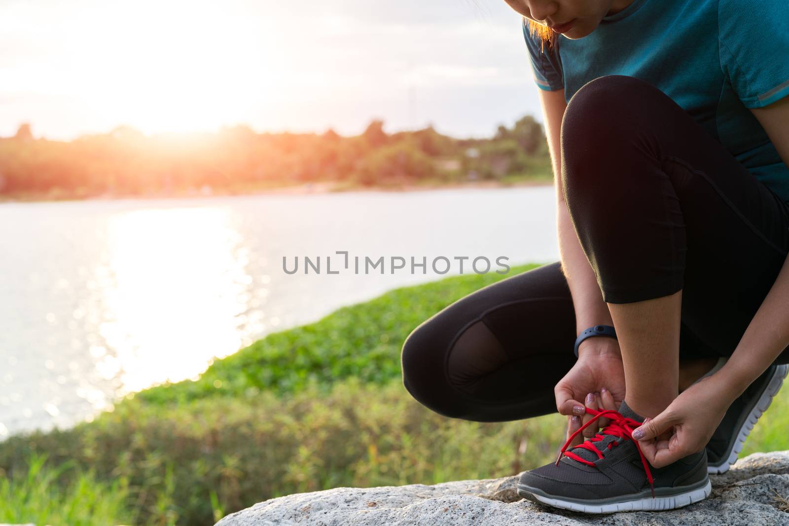 sport woman tying shoelace before running, sunset on the riverside road