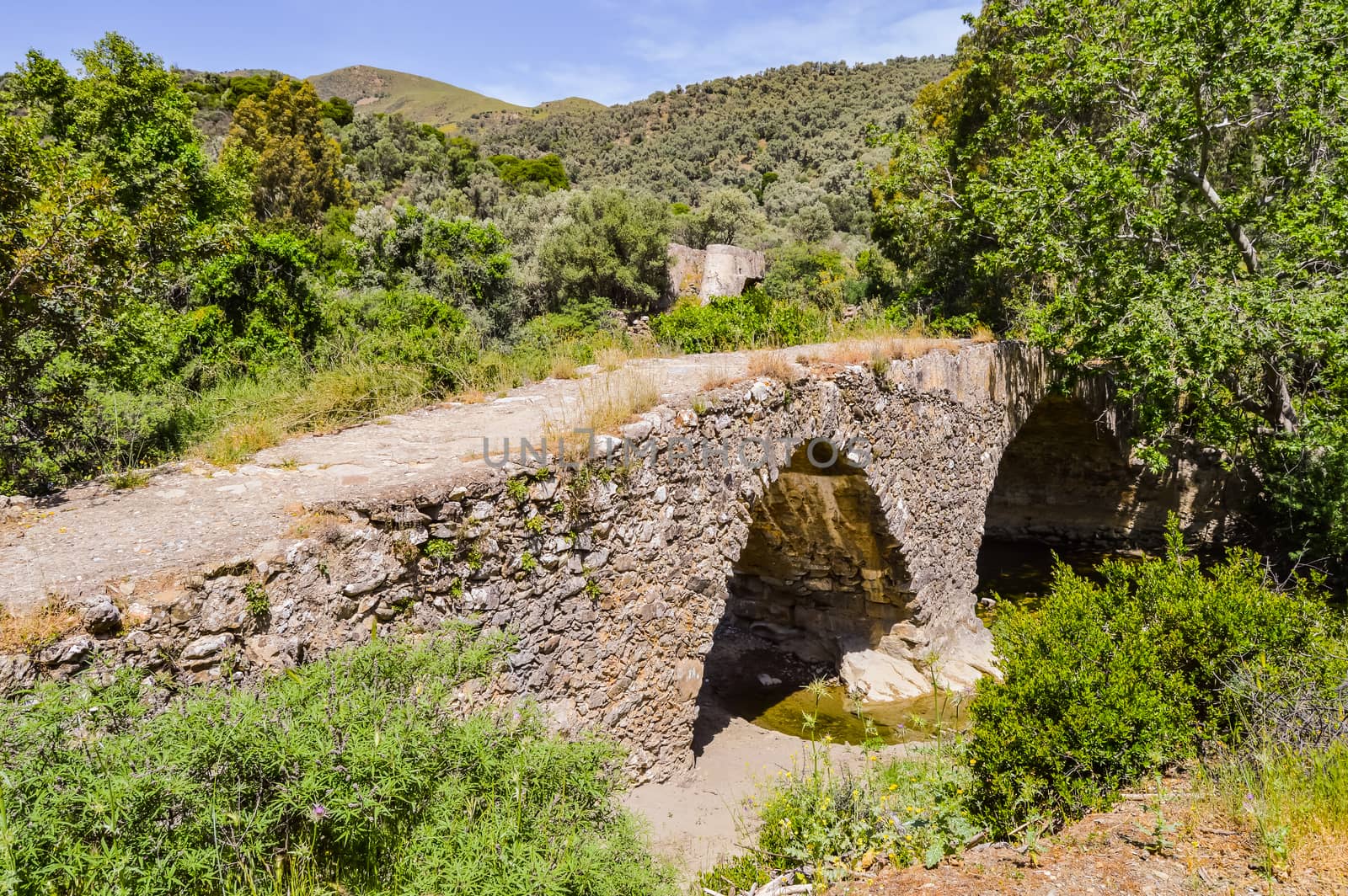 An old stone bridge over a stream in the center of the island of Crete in Greece