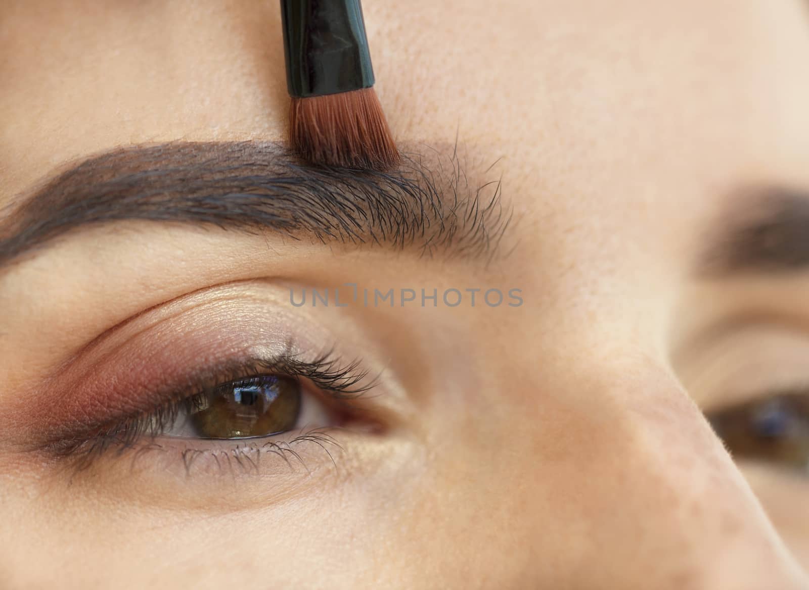 Makeup eyebrows close-up with a soft brush.