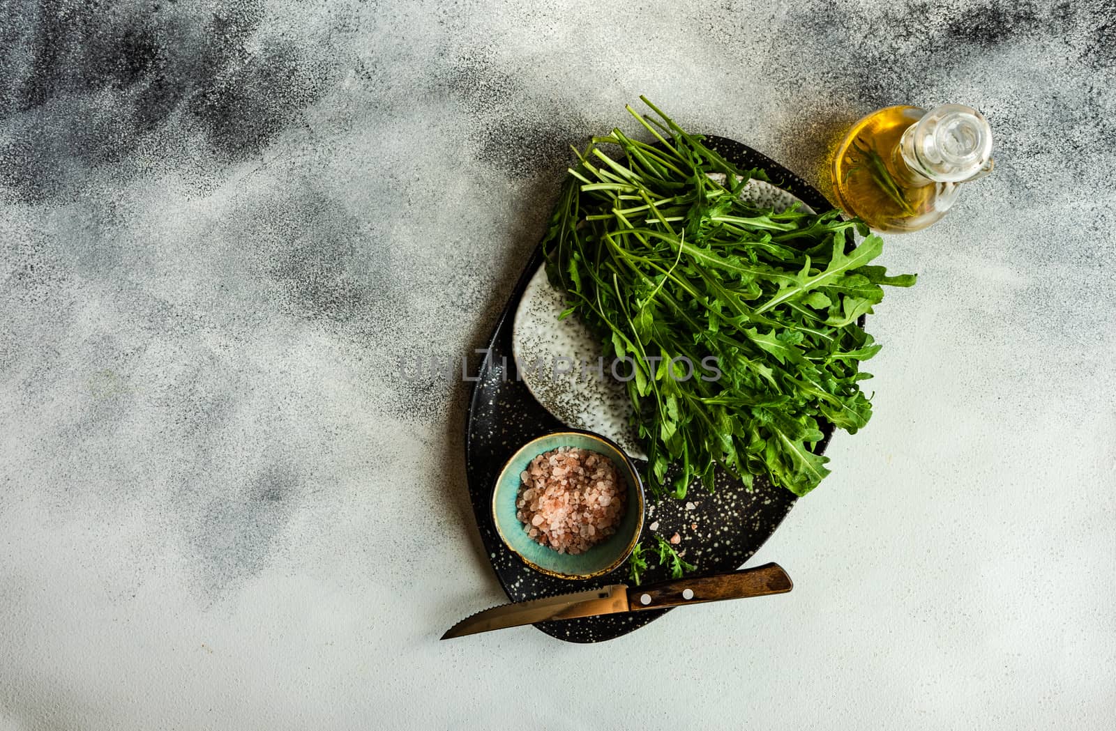 Healthy food concept with fresh organic arugula herb leaves on stone background with copy space