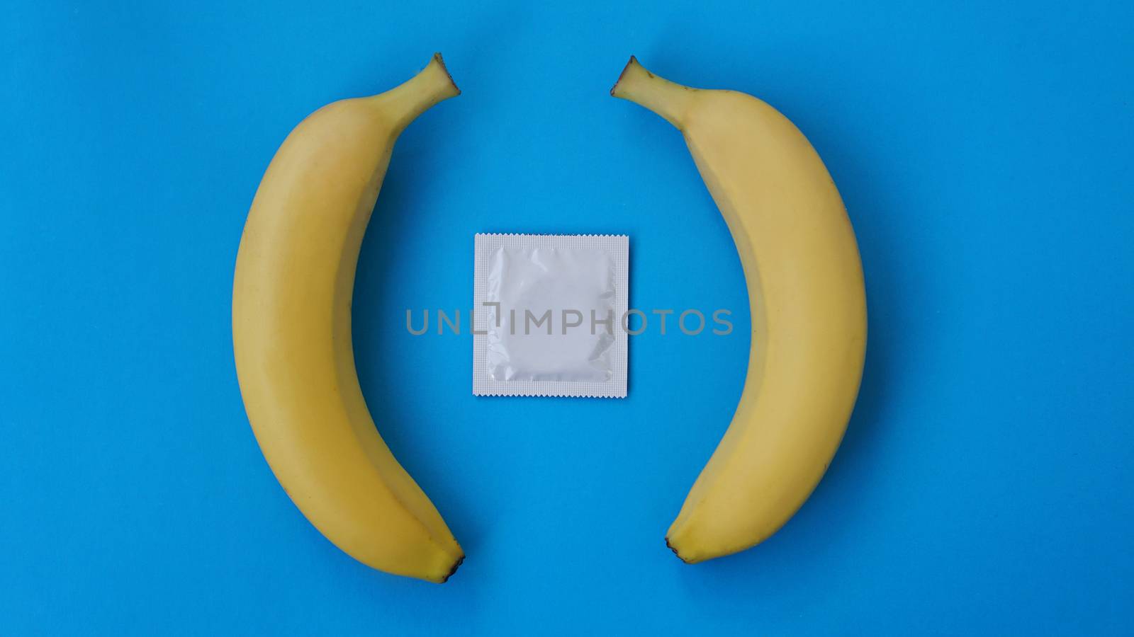 Condoms and two bananas together on blue background, the concept of contraceptives and the prevention of venereal diseases of same-sex marriage.