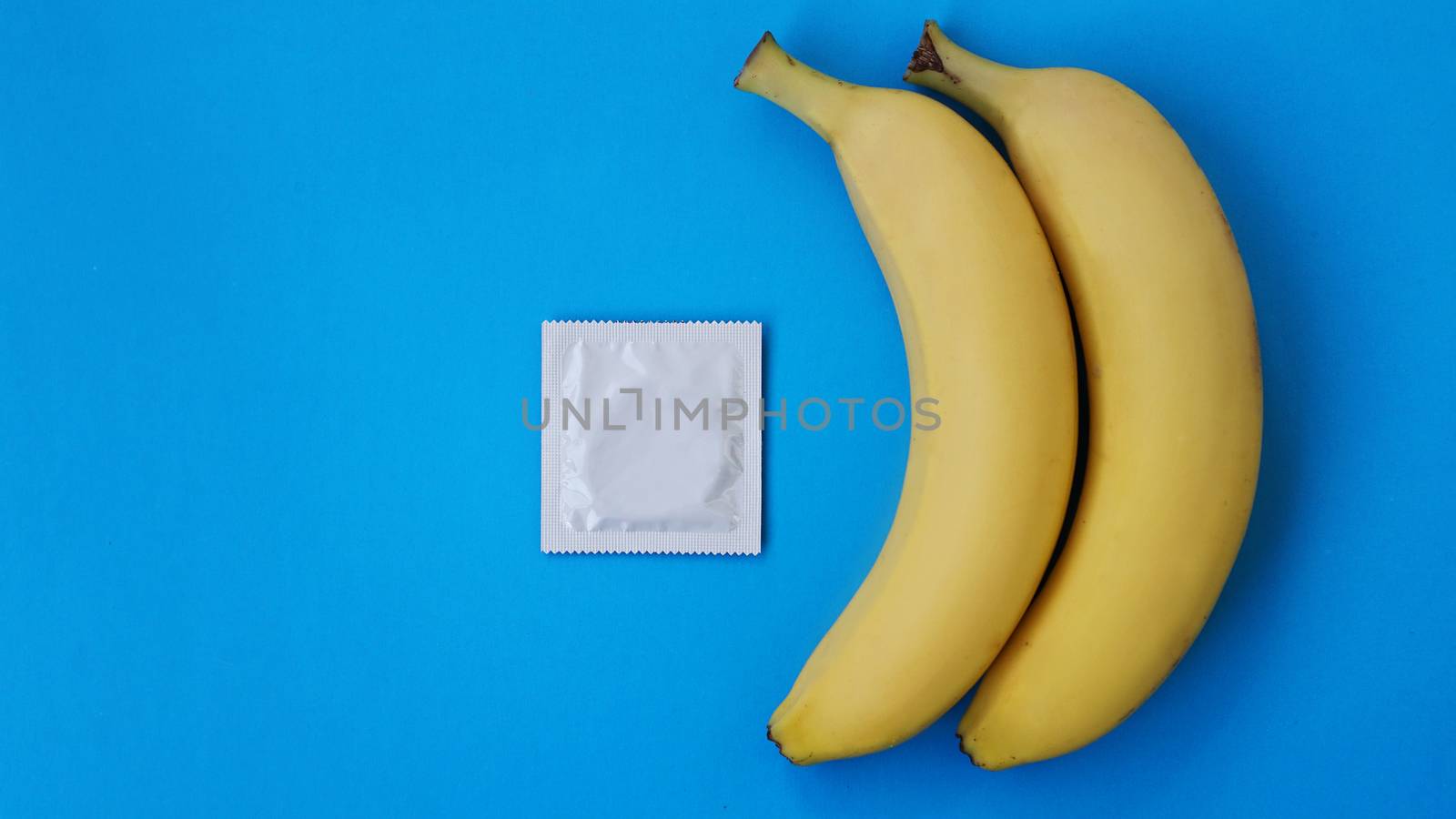 Condoms and two bananas together on blue background, the concept of contraceptives and the prevention of venereal diseases of same-sex marriage.