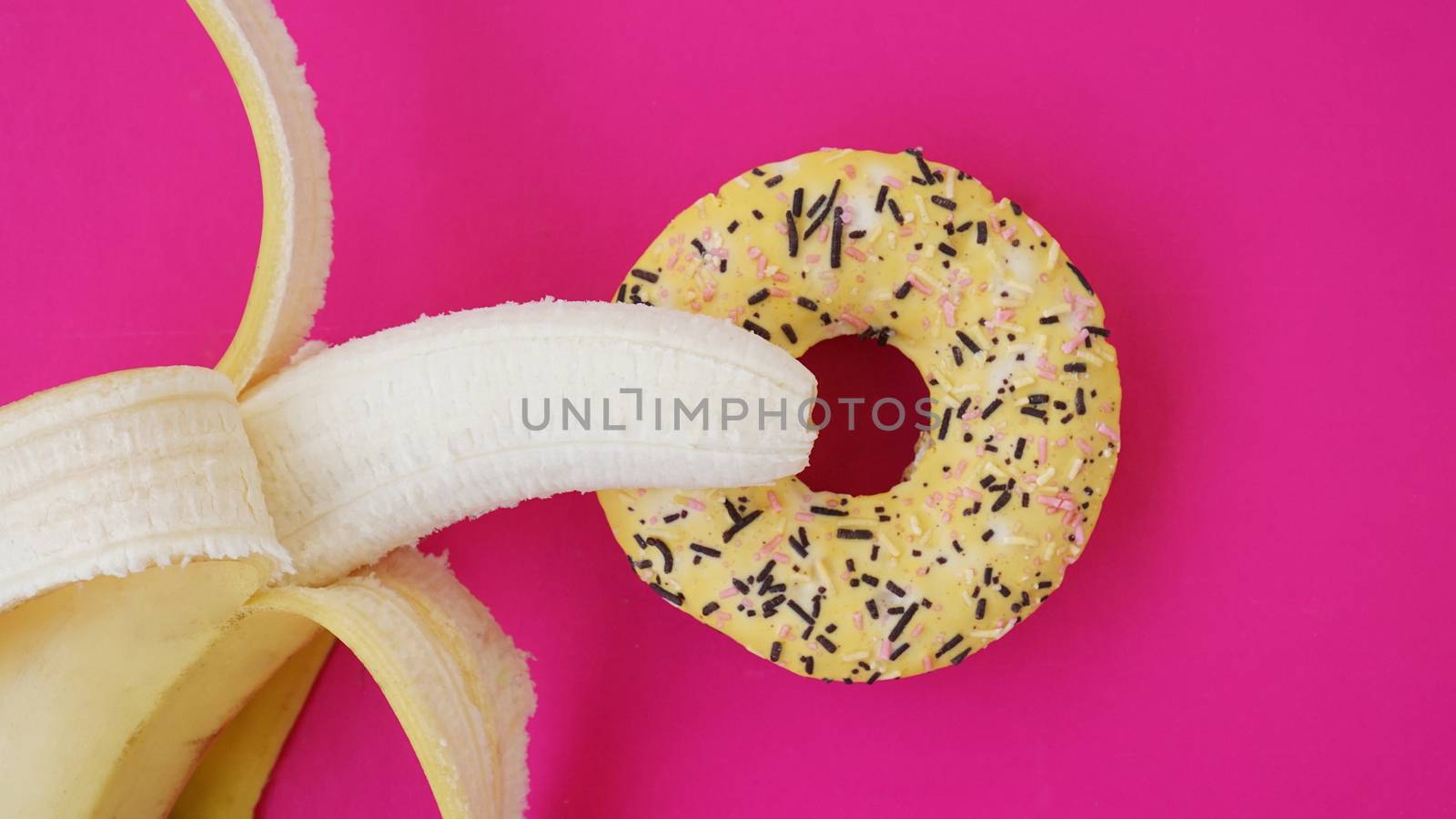 Sweet donut and banana on pink color background. Sex and Erotic concept