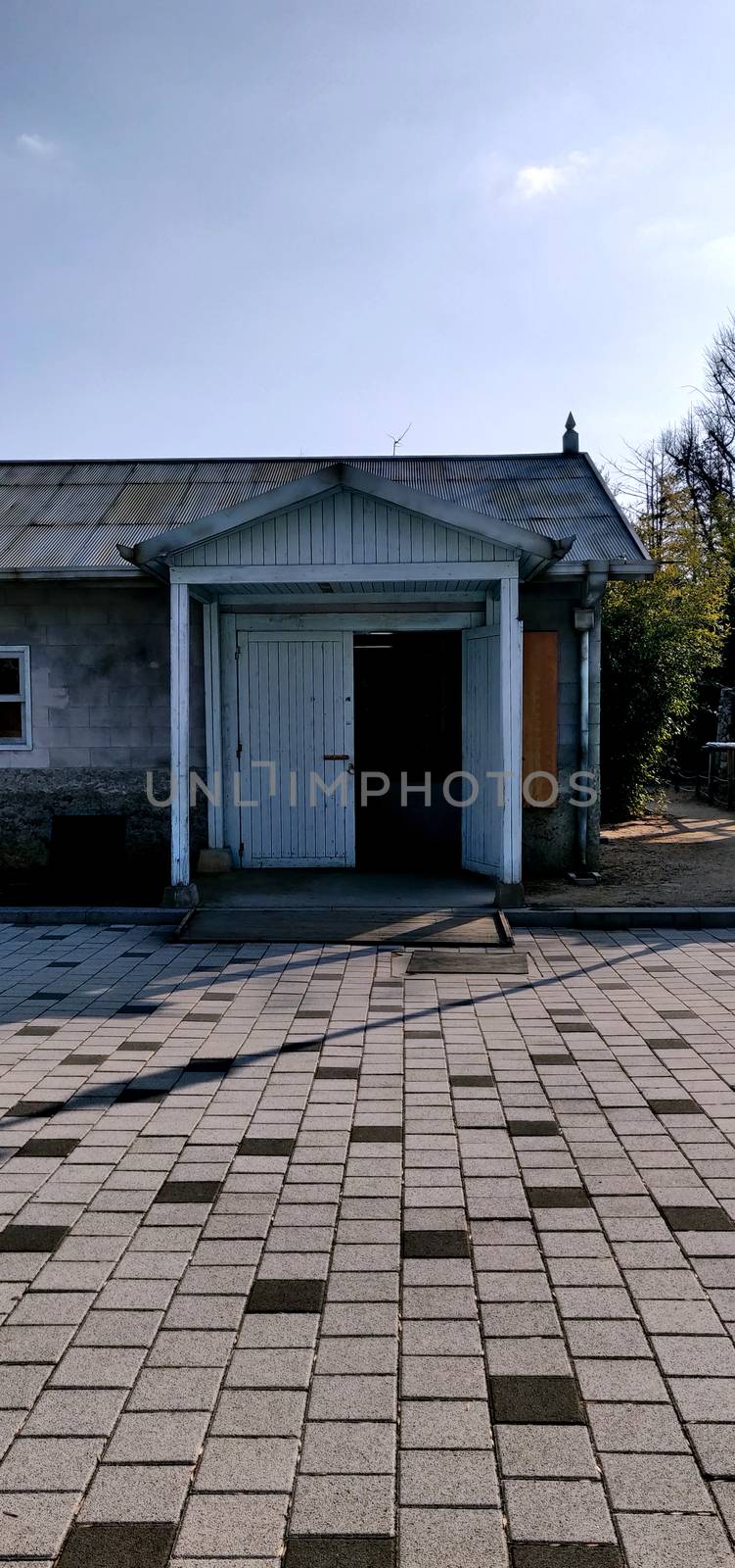 An abandoned old house with white wooden door and brick pavement with tin roof somewhere in Korea