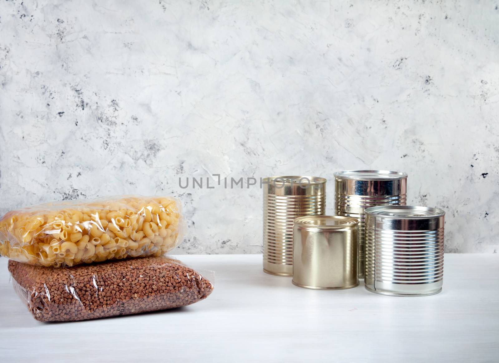 humanitarian assistance for poor and large families. Donation during crisis, pandemic or quarantine. Tin cans, canned food, stew, buckwheat, rice and pasta in transparent bags on white background.