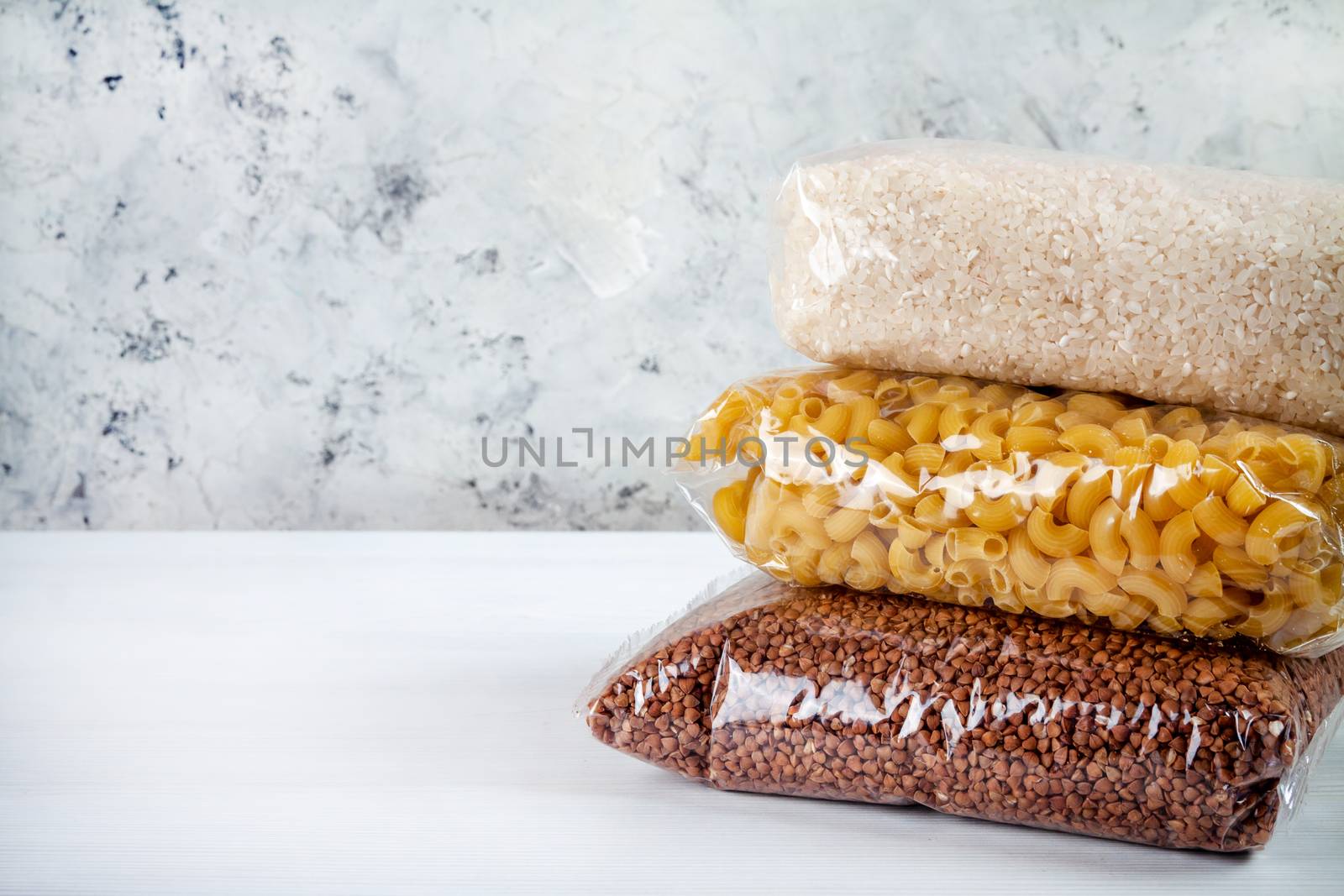 humanitarian assistance for poor and large families. Donation during crisis, pandemic or quarantine. Tin cans, canned food, stew, buckwheat, rice and pasta in transparent bags on white background.