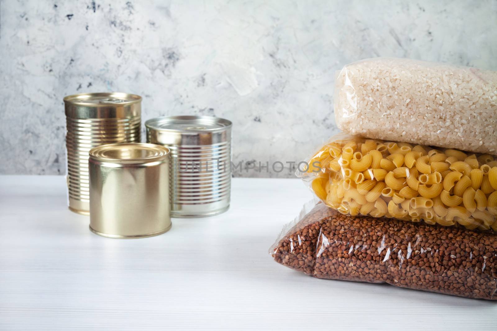 humanitarian assistance for poor and large families. Donation during crisis, pandemic or quarantine. Tin cans, canned food, stew, buckwheat, rice and pasta in transparent bags on white background.
