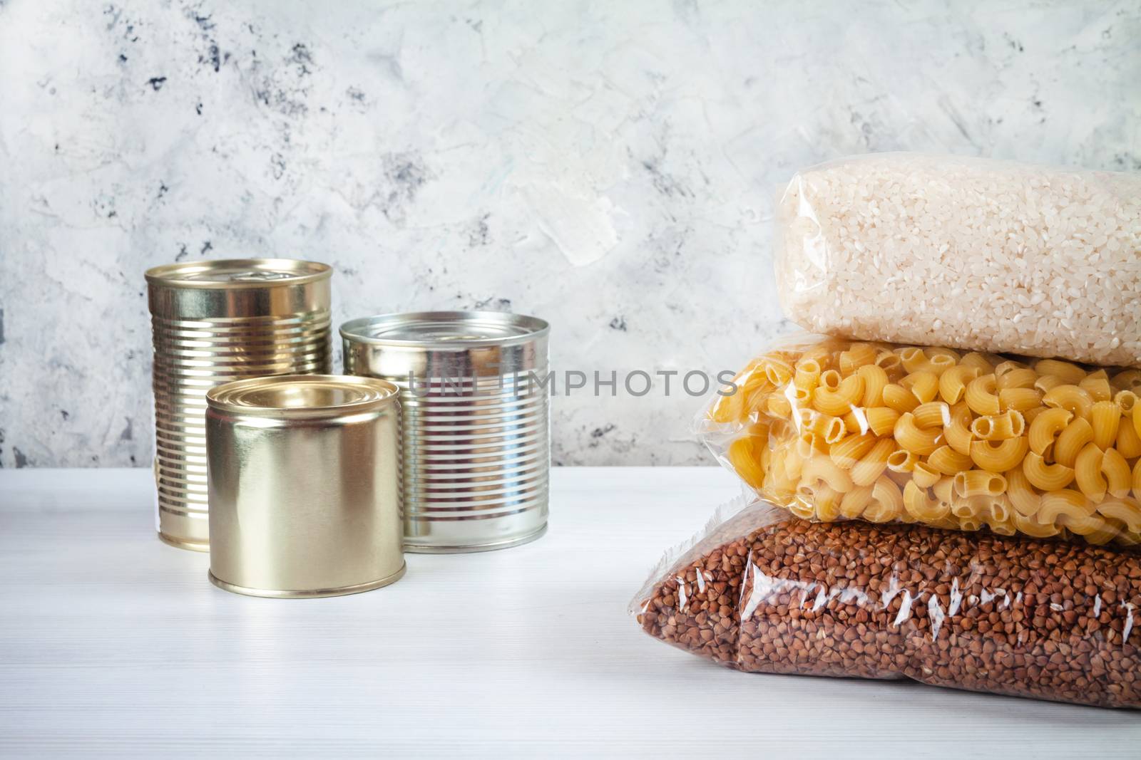 humanitarian assistance for poor and large families. Donation during crisis, pandemic or quarantine. Tin cans, canned food, stew, buckwheat, rice and pasta in transparent bags on white background.