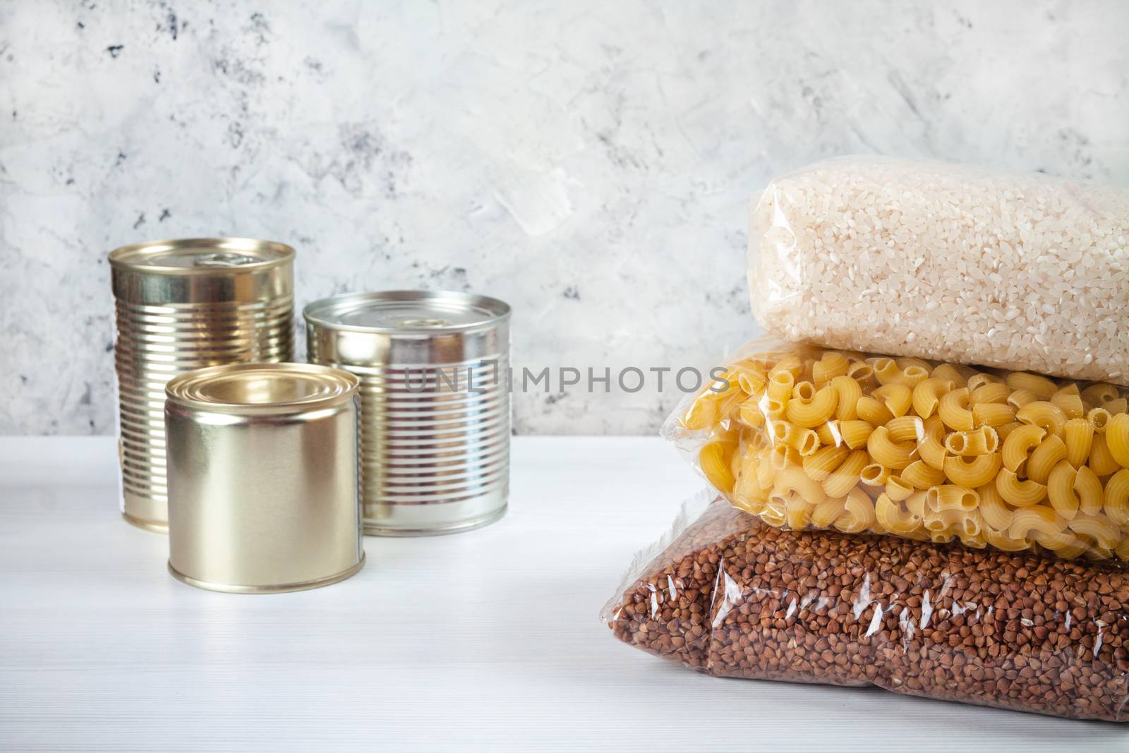 humanitarian assistance for poor and large families. Donation during crisis, pandemic or quarantine. Tin cans, canned food, stew, buckwheat, rice and pasta in transparent bags on white background.