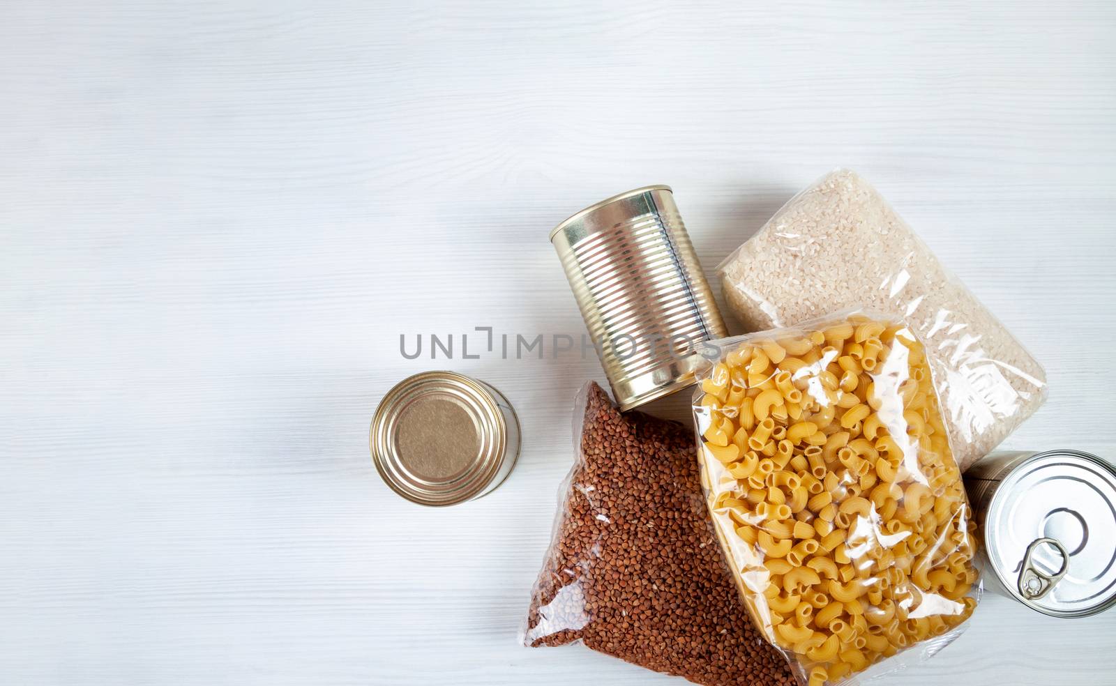 humanitarian assistance for poor and large families. Donation during crisis, pandemic or quarantine. Tin cans, canned food, stew, buckwheat, rice and pasta in transparent bags on white background.