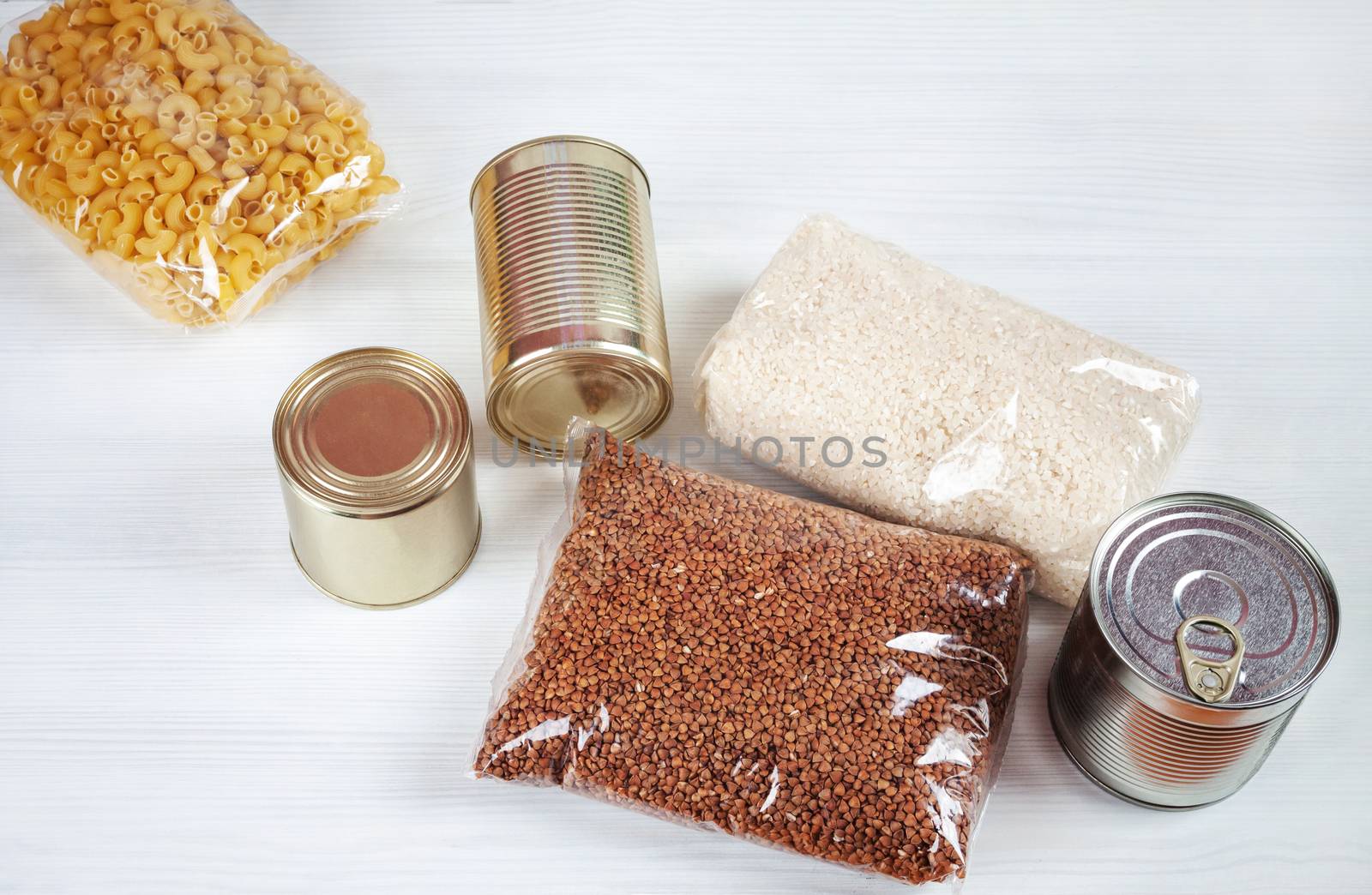 humanitarian assistance for poor and large families. Donation during crisis, pandemic or quarantine. Tin cans, canned food, stew, buckwheat, rice and pasta in transparent bags on white background.