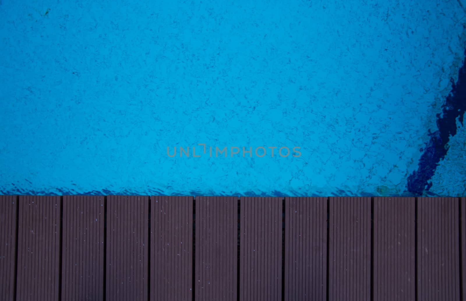blue swimming pool with teak wood flooring stripes summer vacation