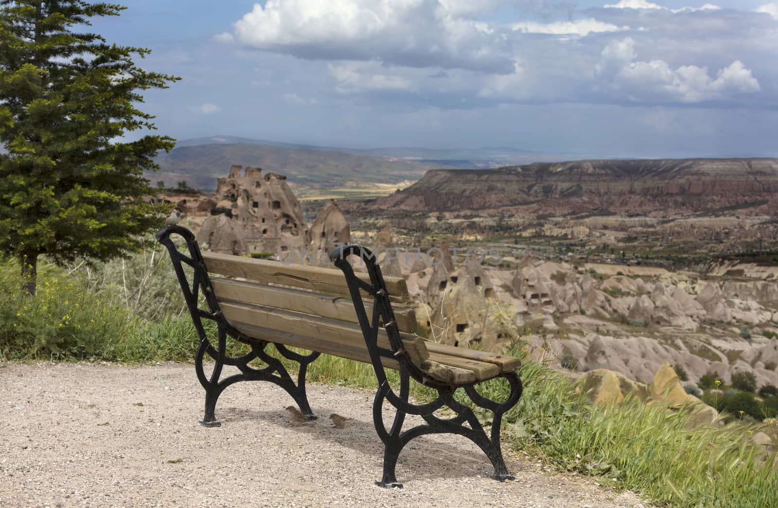 A wooden weathered bench stands against the backdrop of the mountain scenery of Cappadocia