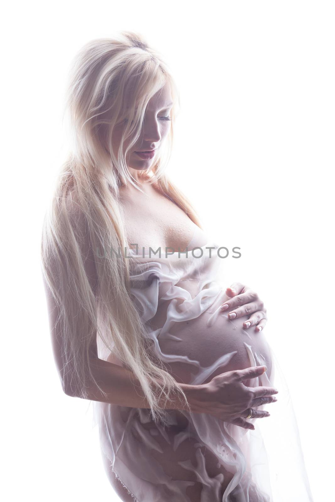 Young pregnant woman in white wet fabric on a studio background