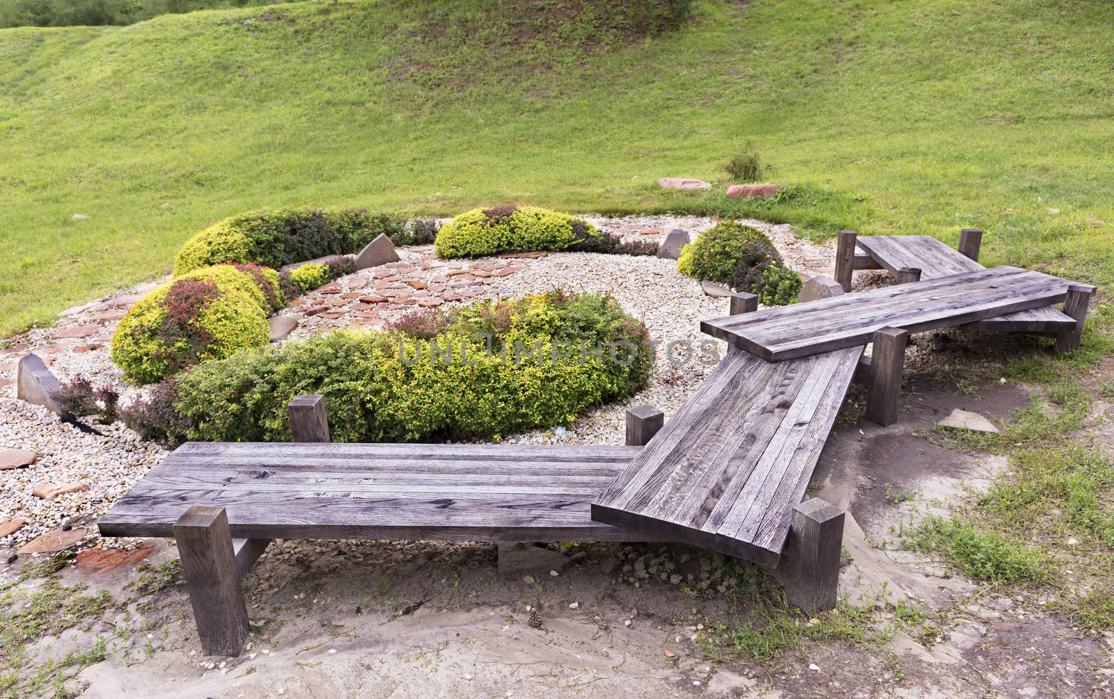 An old originalwooden bench, green bushes in a Japanese rock garden