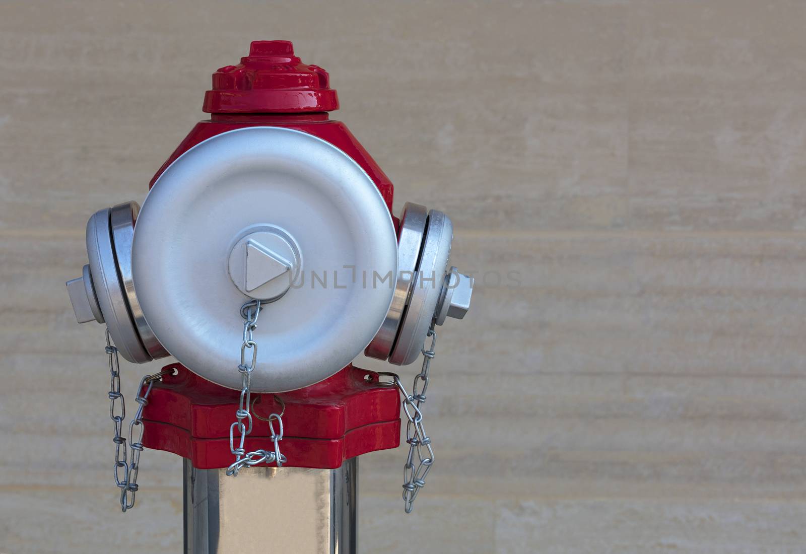 The head of the fire red hydrant with frosted steel caps on the background of the granite wall close-up