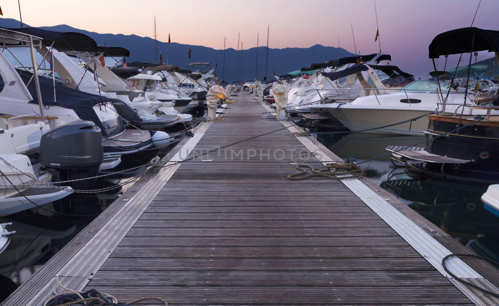 Morning at the sea pier, trail with many moored luxury and expensive yachts in the port of Budva, Montenegro.