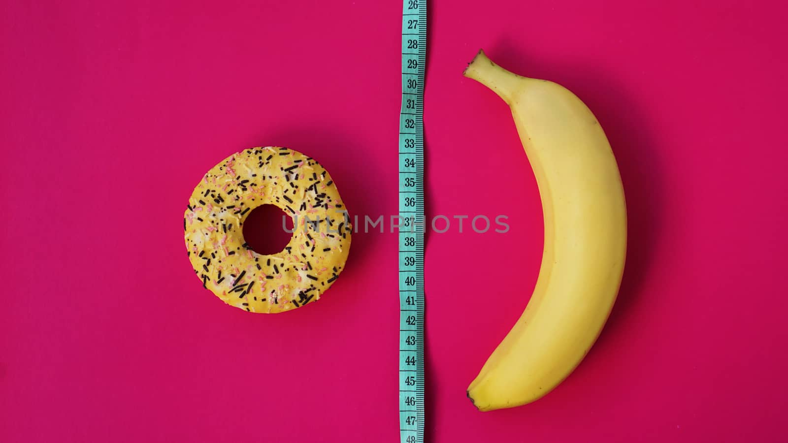 Two types of food, healthy and unhealthy, banana and donut, diet and obesity, health concept on a pink background