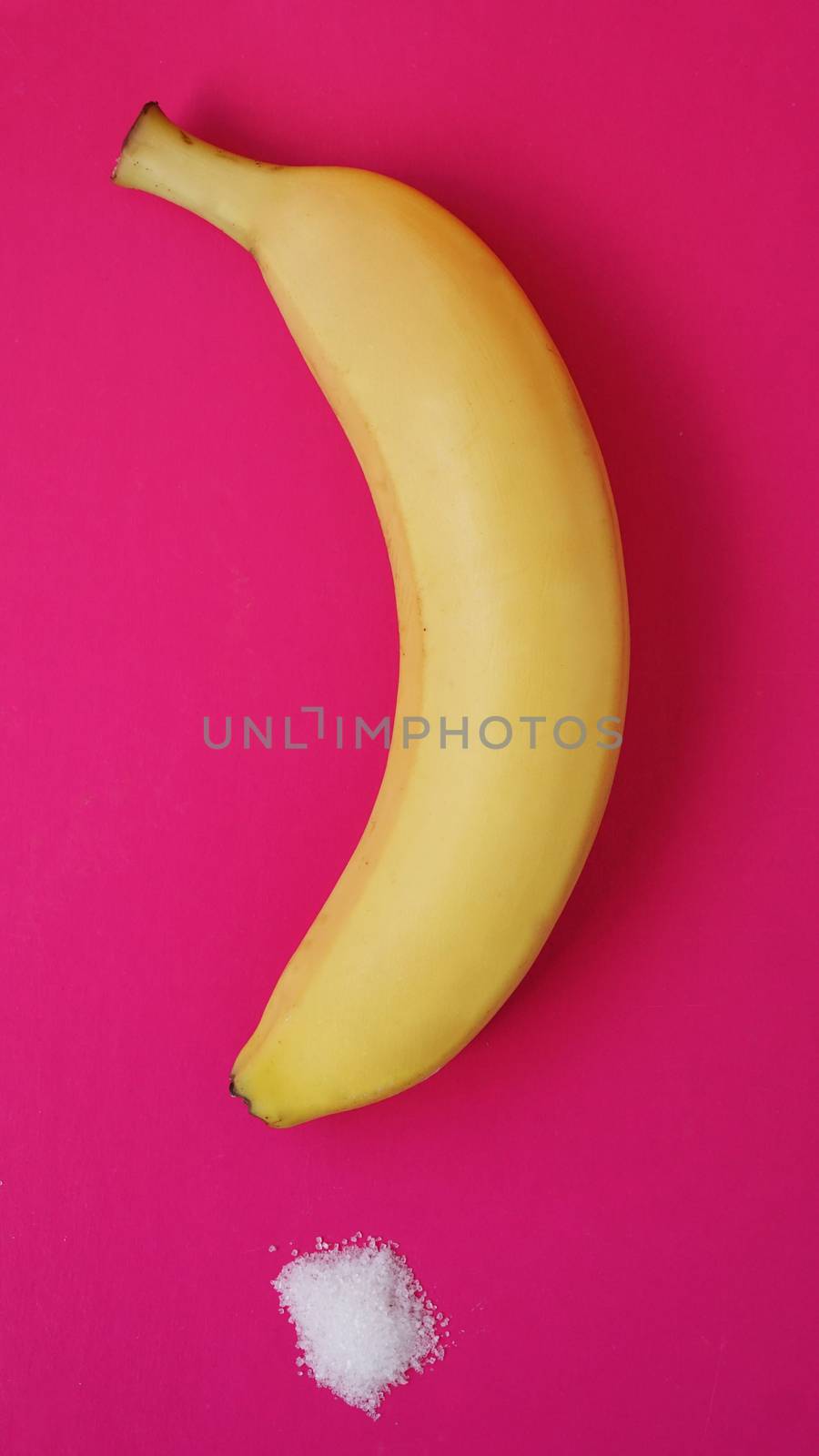 Banana and sugar on a pink background. Diet and healthy eating concept.