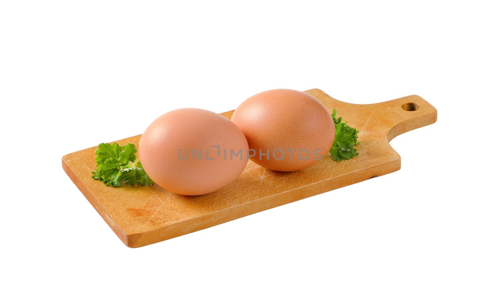 Two brown eggs on wooden cutting board isolated on white