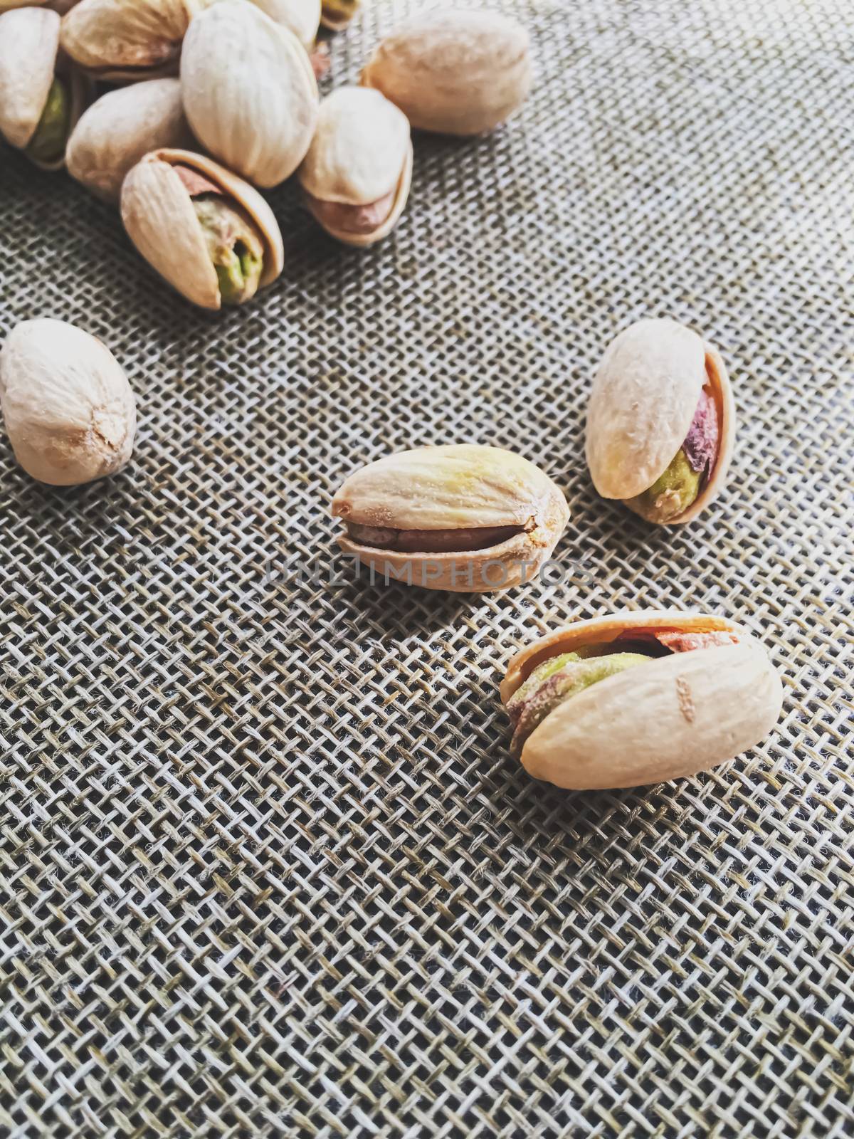 Pistachio nuts on rustic linen background by Anneleven