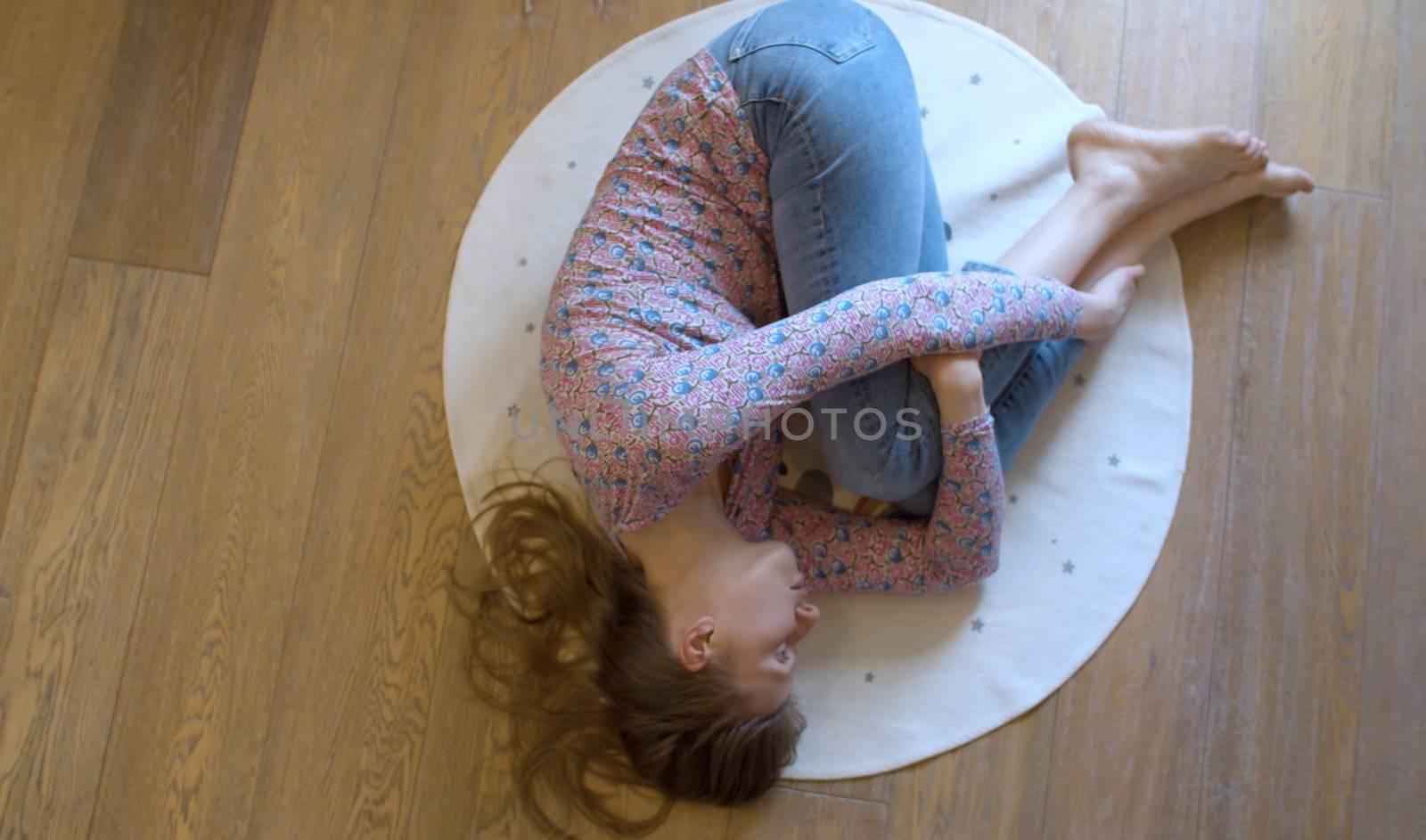 Woman lying on a round carpet, top view. Round rug with the inscription - this is my happy place. Personal space symbol.