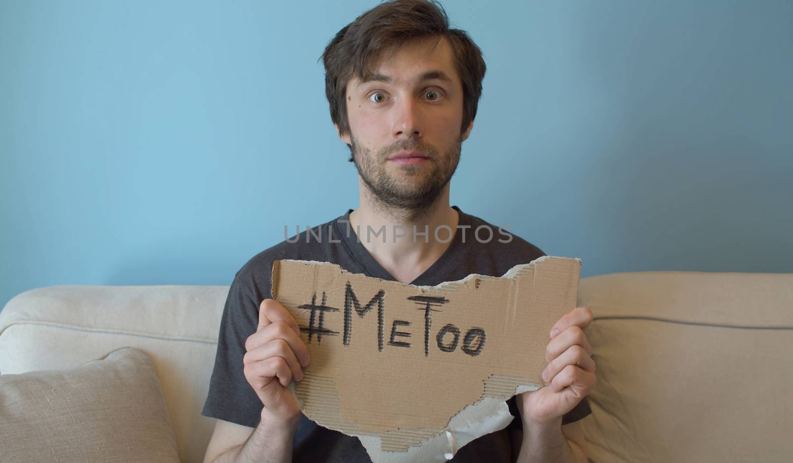 Young man holding a piece of cardboard with hashtag me too. Movement against sexual harassment.